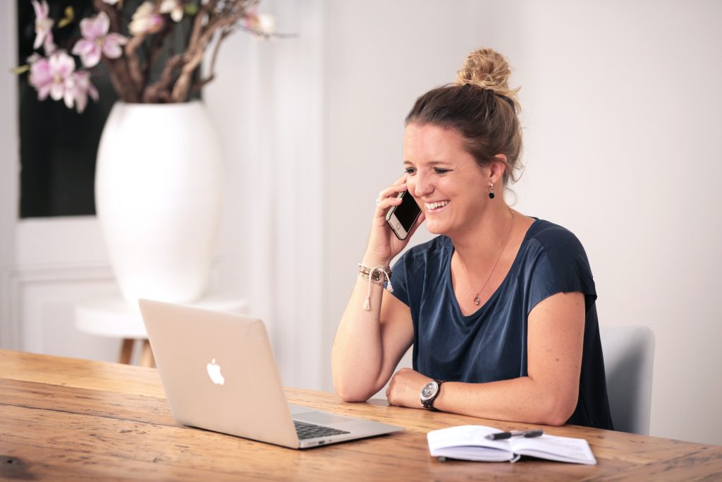 Wendy met telefoon achter laptop